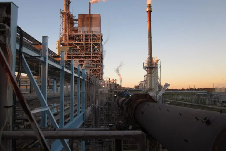 Industrial processing facility at sunset with visible emissions and large ductwork, illustrating complex air pollution control needs such as the venturi wet scrubber.